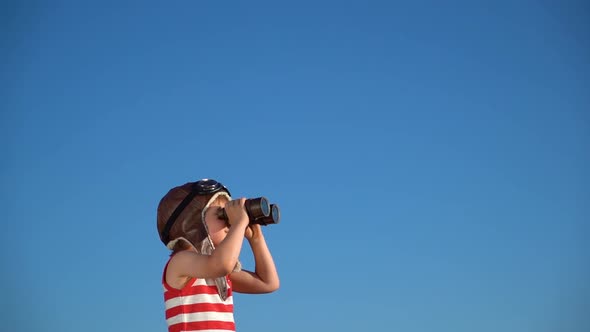 Kid with binoculars having fun outdoor against blue summer sky. Explore and discovery concept