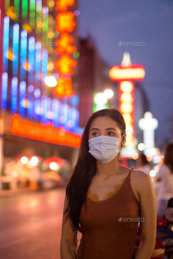 Young Asian tourist woman thinking with mask for protection from corona virus outbreak in Chinatown