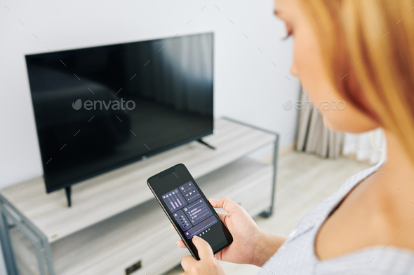 Woman checking tv volume settings - Stock Photo - Images