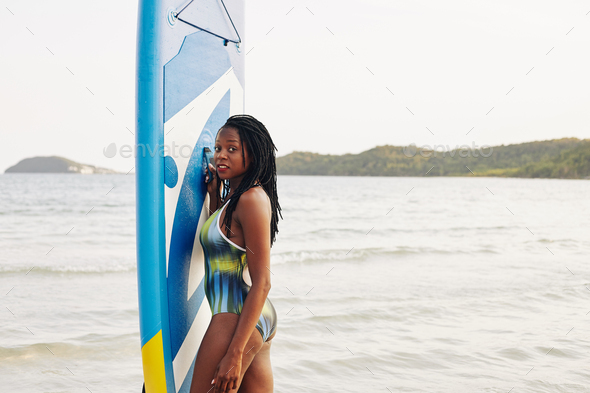 Woman posing with sup surfing board