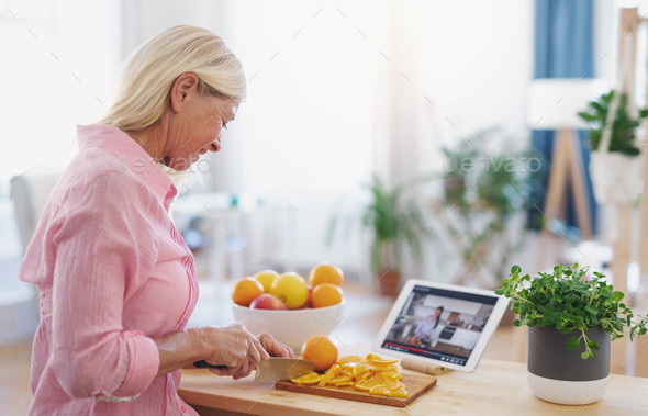 Senior woman preparing food in kitchen indoors, following food vlogger