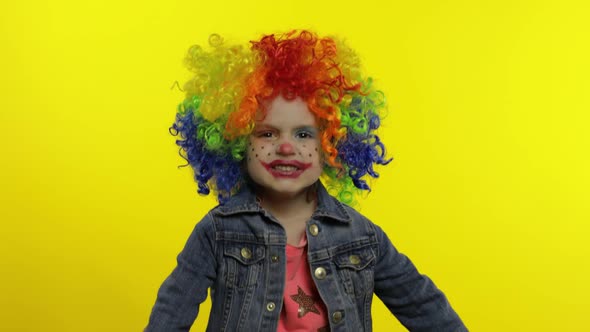 Angry Little Child Girl Clown in Colorful Wig Making Evil Faces. Having Fun. Halloween. Expressions alt