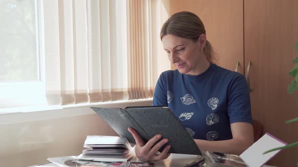Woman Looks Through Old Family Photos in Album and Reminisces About Past Time