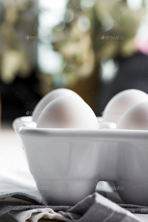 Ceramic container with natural organic farm eggs on a blurred kitchen  background Stock Photo by lyulkamazur