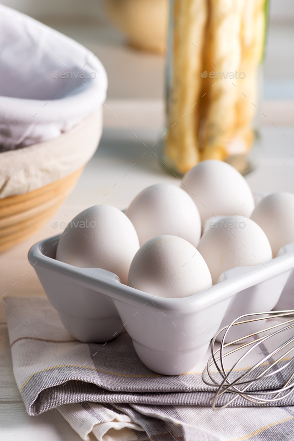 Ceramic container with natural organic farm eggs on a blurred kitchen  background Stock Photo by lyulkamazur