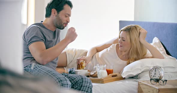 Beautiful Man and Woman Eating Breakfast with Brioches in Bed