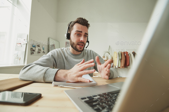 Young operator with headset explaining something during online consultation  Stock Photo by Pressmaster
