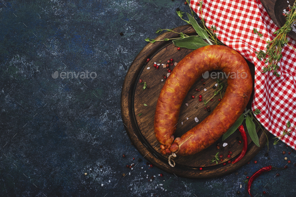 Smoked sausage on grey kitchen table background with aromatic herbs and spices - Stock Photo - Images