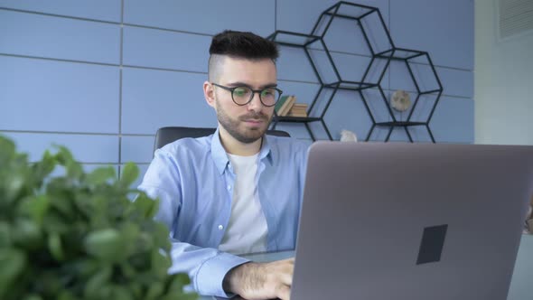 Professional Creative Man Sitting at His Desk in Home Office Studio Working on a Laptop alt