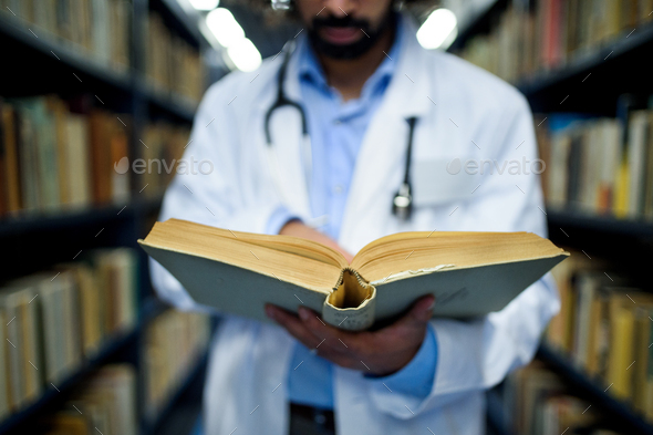 Unrecognizable doctor in library, studying information about corona virus