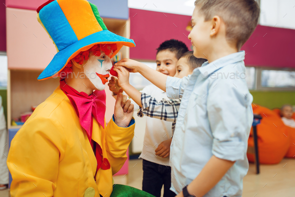 Little joyful boy touches red clown's nose - Stock Photo - Images
