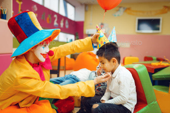 Funny clown puts a cap on the little boy's head - Stock Photo - Images