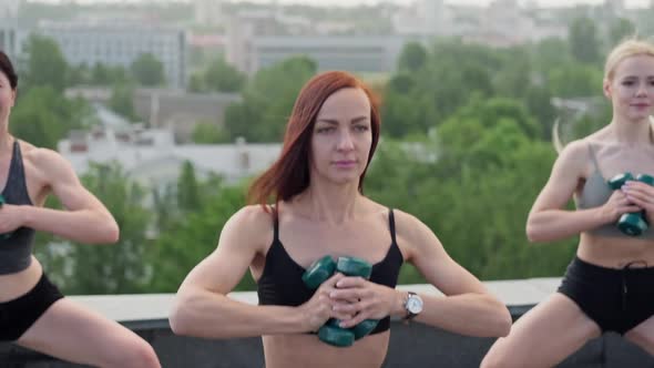 Fitness Females Making Squats on Roof of Building alt