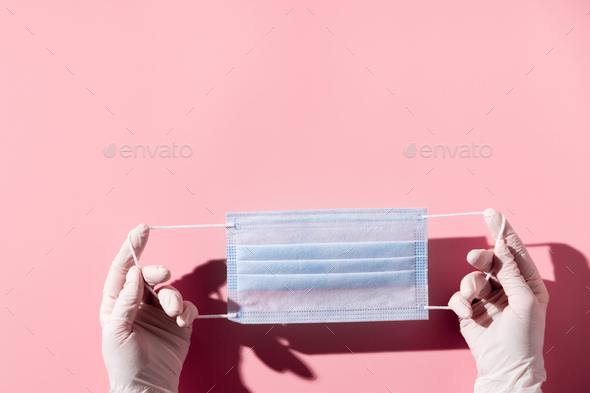 Woman hands in latex gloves holding facial medical mask, pink background, close up, copy space - Stock Photo - Images