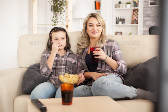 Mother and daughter watching a movie sitting on the couch