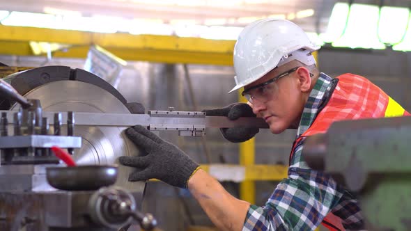 Male engineer metalworker operating work on lathe machine,