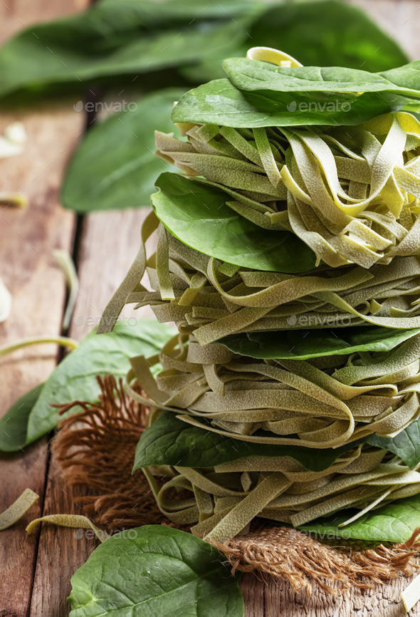 Dry spinach pasta with green leaves, folded like a tower