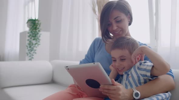 Mother and Son Sitting on Sofa Using Digital Tablet alt