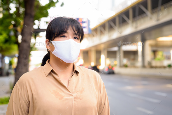 Overweight Asian woman with mask for protection from corona virus outbreak in the city streets