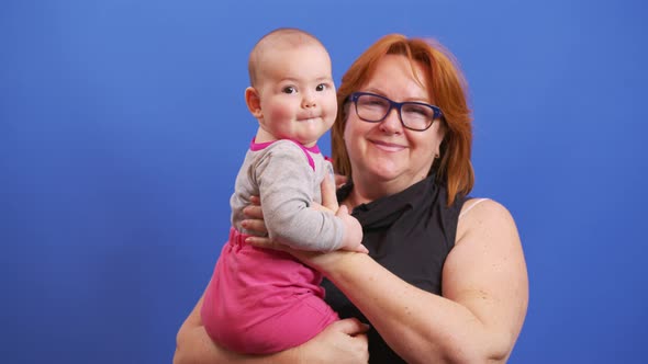 Senior Woman Holding Her Baby Granddaughter Kiss at Home Young and Old People Together alt