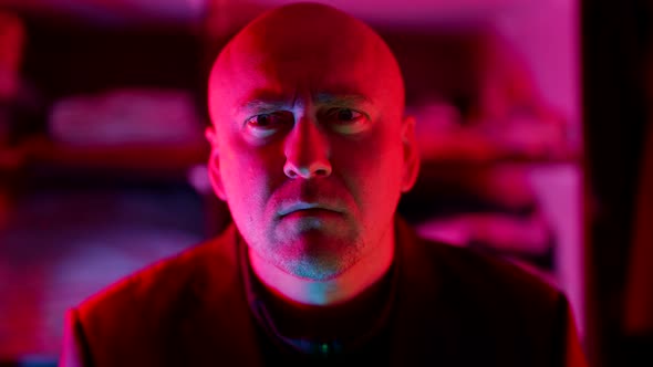 a Bald Man Looks Frowningly at the Camera Then Starts Laughing Hysterically in a Flashing alt
