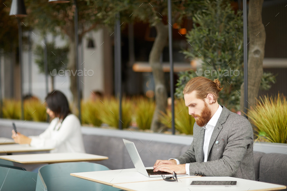 Businessman sitting in online cafe - Stock Photo - Images
