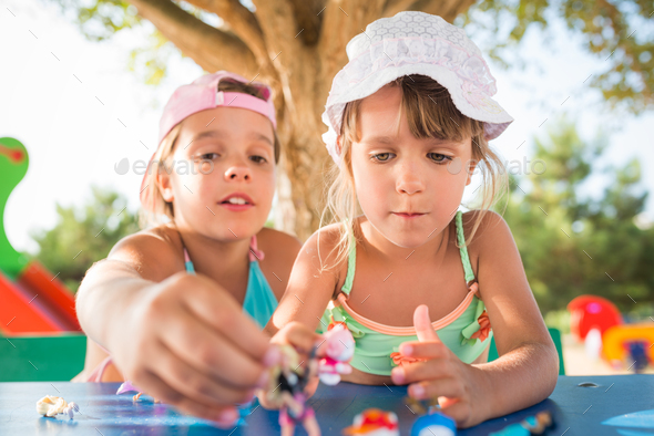 Two little cute girls playing dolls outdoors - Stock Photo - Images