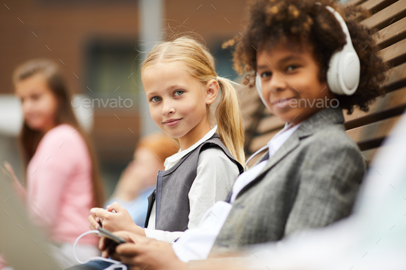 Schoolgirl with her classmate outdoors - Stock Photo - Images