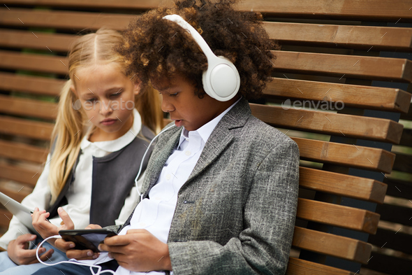 Schoolboy listening to audio lesson on the phone - Stock Photo - Images
