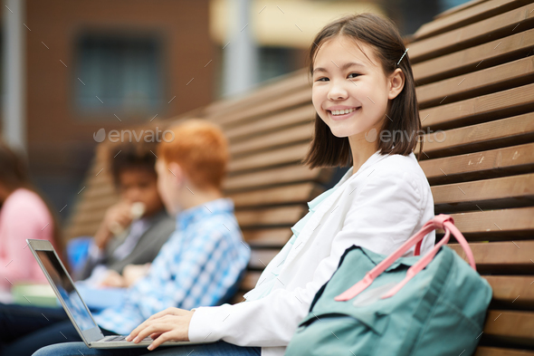 Schoolgirl with laptop outdoors - Stock Photo - Images