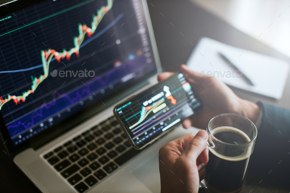 investment stockbroker predicting bitcoin price trend movement using laptop and phone - Stock Photo - Images