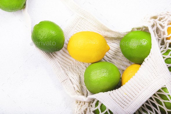 Organic lemons and limes in reusable eco-friendly string mesh bag - Stock Photo - Images