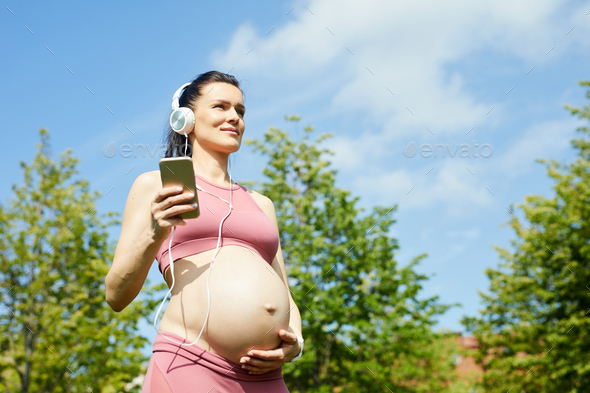 Pregnant woman enjoying the music - Stock Photo - Images