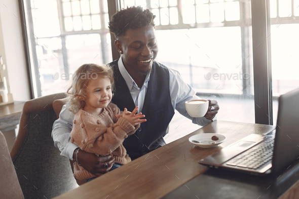 Black man with white daughter standing in a cafe
