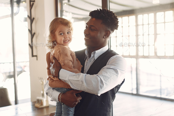 Black man with white daughter standing in a cafe