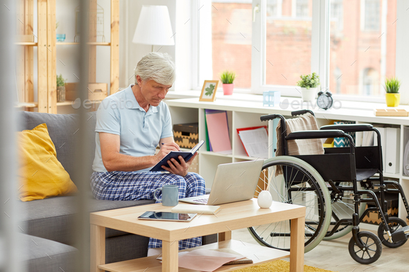 Senior man writing in notepad - Stock Photo - Images