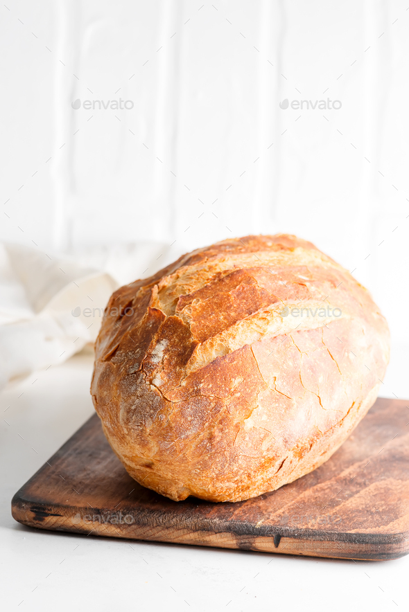 Homemade freshy baked bread on a wooden board and light grey marble table decorated textile towel - Stock Photo - Images