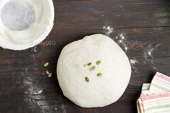 Homemade freshly prepared raw bread with pumpkin seed in a basket on a wooden dark background - Stock Photo - Images