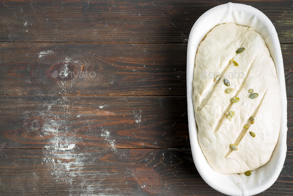 Homemade freshly prepared raw bread with pumpkin seed in a basket on a wooden dark background - Stock Photo - Images
