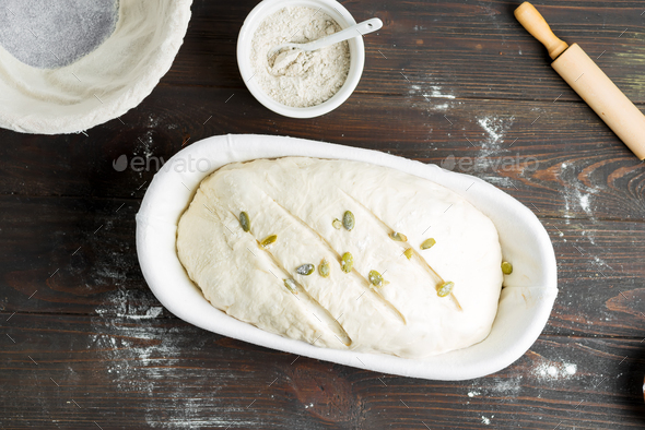Top view of homemade freshly cooked raw loaf with pumpkin seed in a basket on a wooden dark - Stock Photo - Images