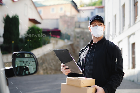 Delivery man courier with face mask delivering parcel box in town