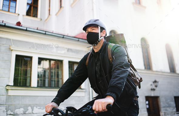Delivery man courier with face mask and bicycle cycling in town