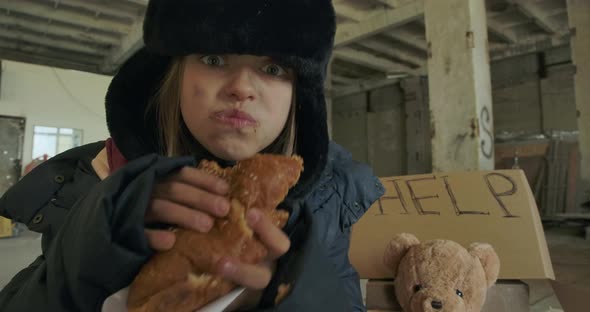 Portrait of Ukrainian Refugee with Dirty Face and Grey Eyes Greedily Eating the Bun alt