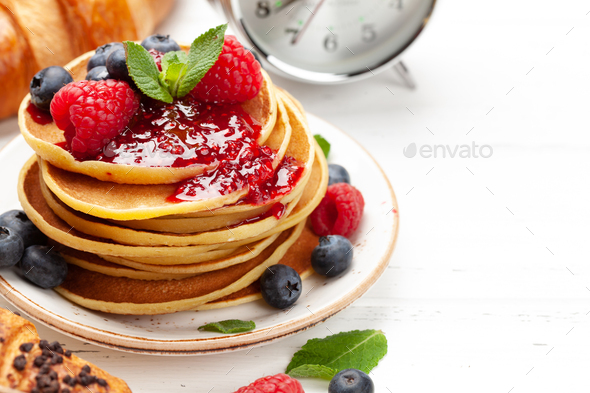 Delicious pancakes with berries and jam, croissants and coffee - Stock Photo - Images