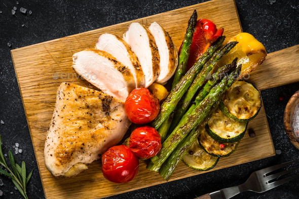 Chicken breast grilled with vegetables on black table - Stock Photo - Images