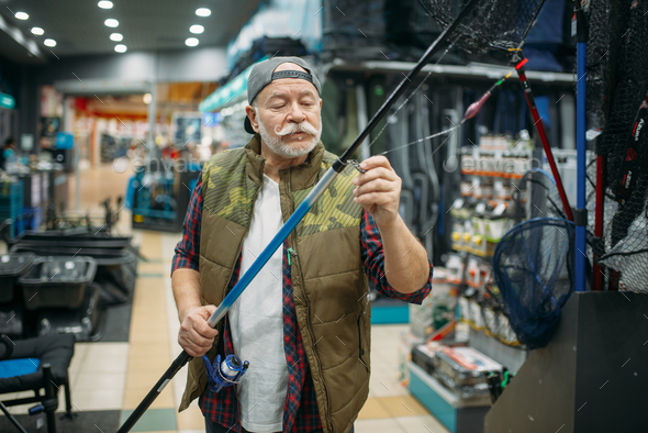 Angler puts line in the eye of rod, fishing shop - Stock Photo - Images