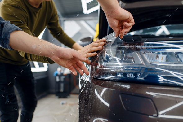Workers applies car protection film on fender - Stock Photo - Images