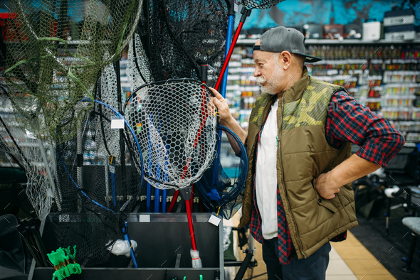Happy fisherman choosing net in fishing shop - Stock Photo - Images