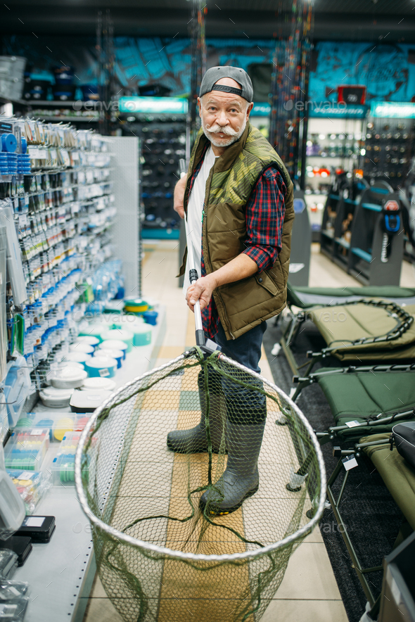 Happy angler holds net in fishing shop - Stock Photo - Images