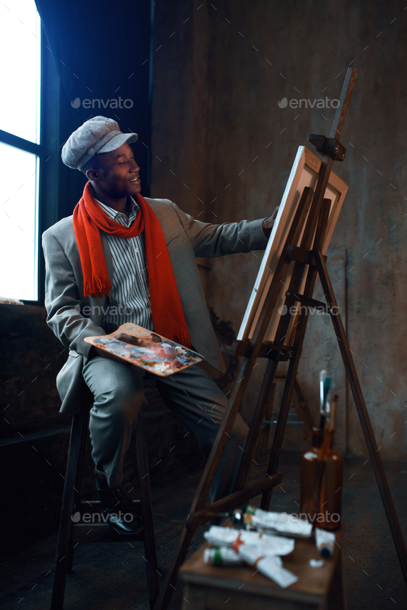 Fashionable painter with palette poses at easel - Stock Photo - Images
